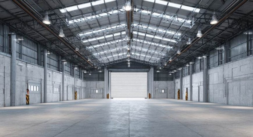 Galpão industrial amplo com estrutura metálica, pé-direito alto e iluminação natural para operações logísticas e armazenamento